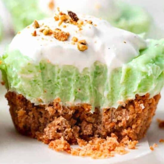 A close up of a green pistachio pie with whipped cream on top in small cups.