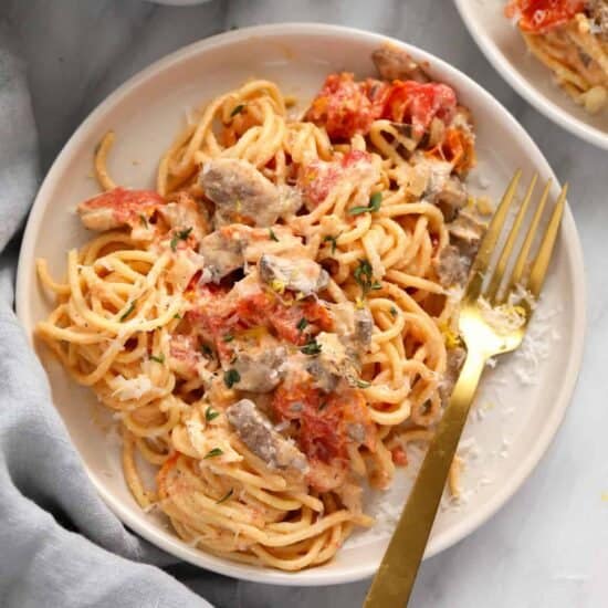 A baked plate of cream cheese pasta with tomatoes.