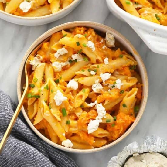 two bowls of pasta with carrots and feta cheese.