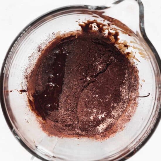 chocolate batter in a glass bowl on a white surface.