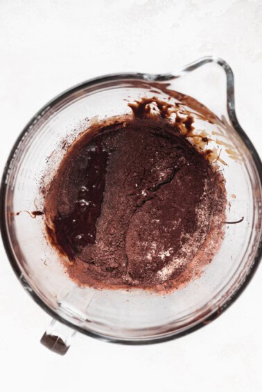 chocolate batter in a glass bowl on a white surface.