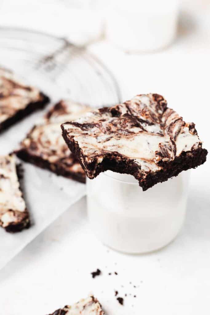 Cream cheese brownie sitting on a glass of milk. 