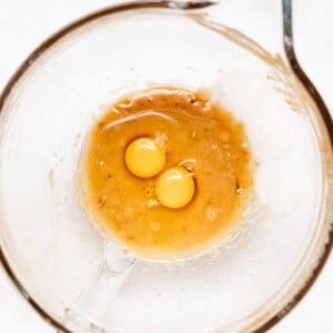 two eggs in a glass bowl on a white surface.