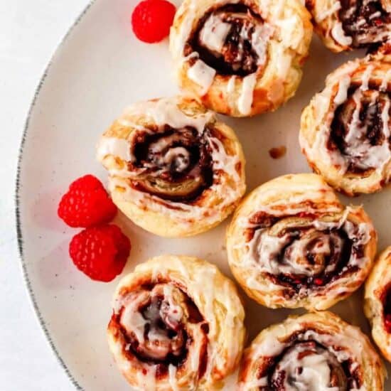 chocolate raspberry cinnamon rolls on a white plate with fresh raspberries