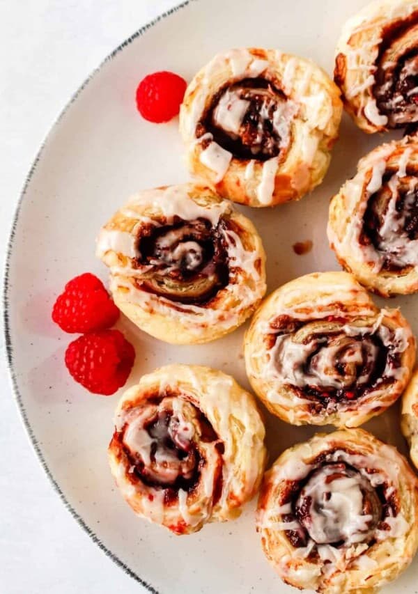 chocolate raspberry cinnamon rolls on a white plate with fresh raspberries