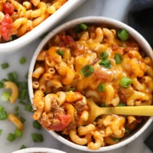 two bowls of macaroni and cheese casserole with a fork.