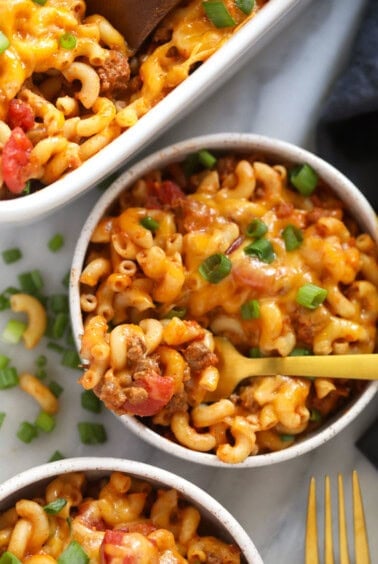 two bowls of macaroni and cheese casserole with a fork.