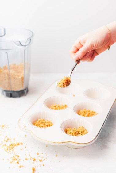 a person scooping granola into pistachio pie cups.