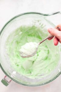 A person mixing pistachio frosting in a bowl.