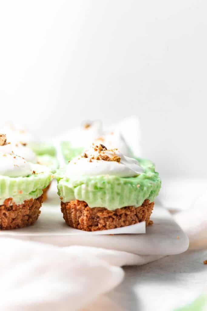 Pistachio pie cups with a dollop of whip and sprinkle of pistachios on top.