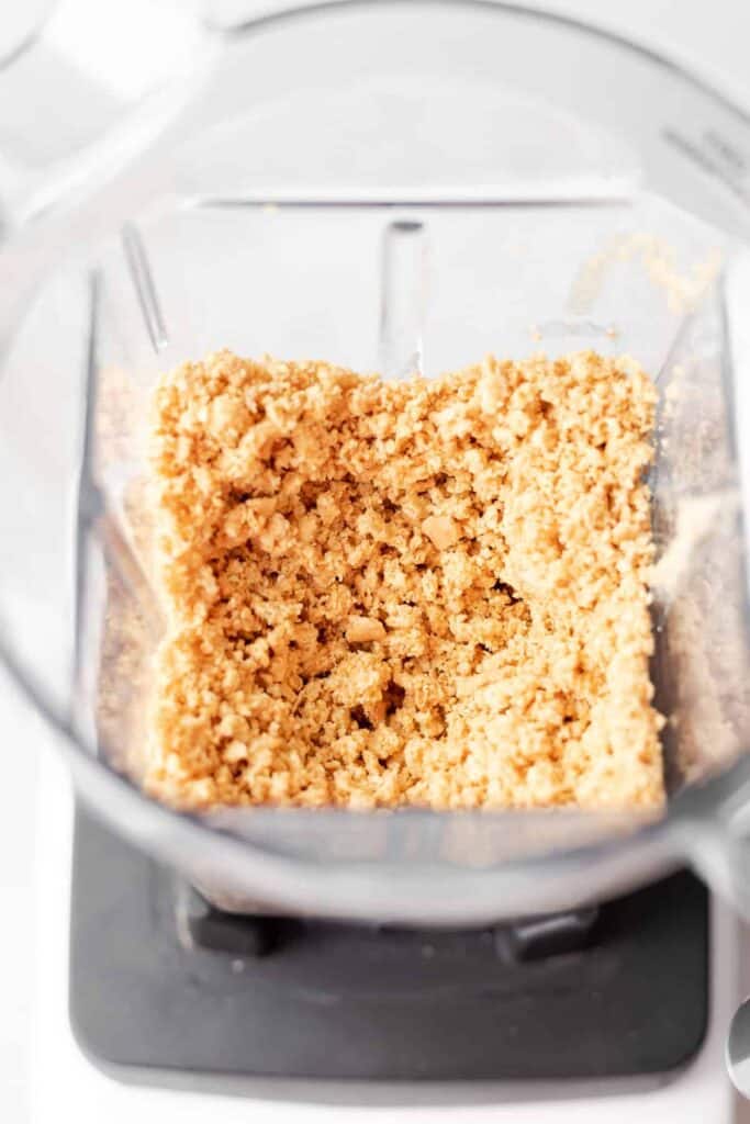 Graham cracker crust in a food processor being blended to crumbly perfection.