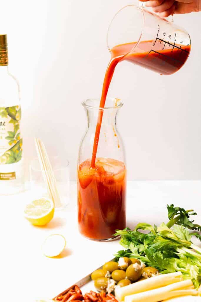 tomato juice being poured in a pitcher for bloody marys