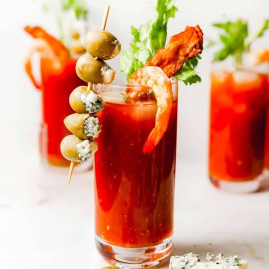 A bacon and olive bloody mary garnished with a skewer.