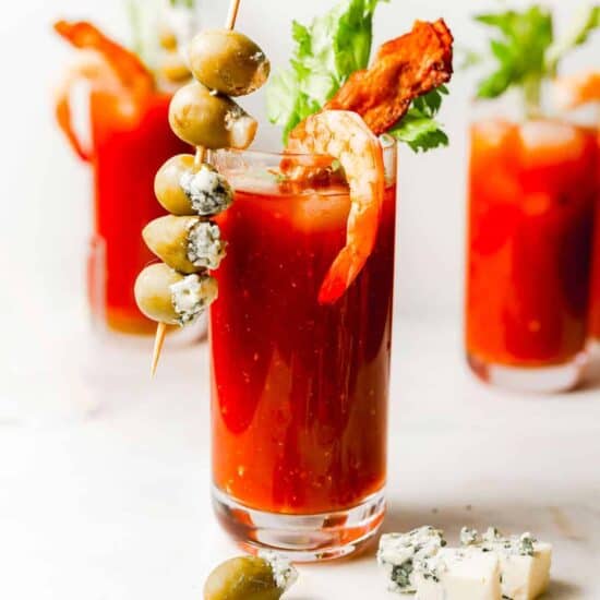 a bloody mary with shrimp and olives served on bloody mary skewers.
