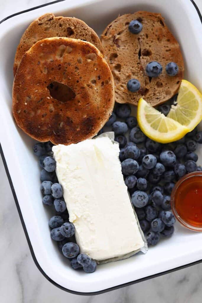 A tray of cream cheese, bagels, and blueberries. 