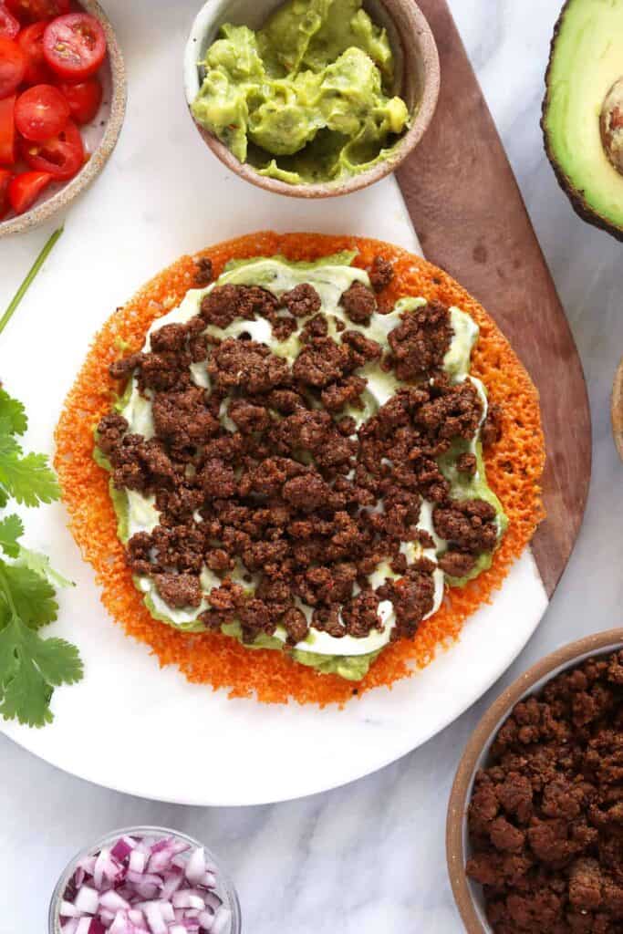 Greek yogurt, guacamole, and ground beef on a cheese tortilla. 