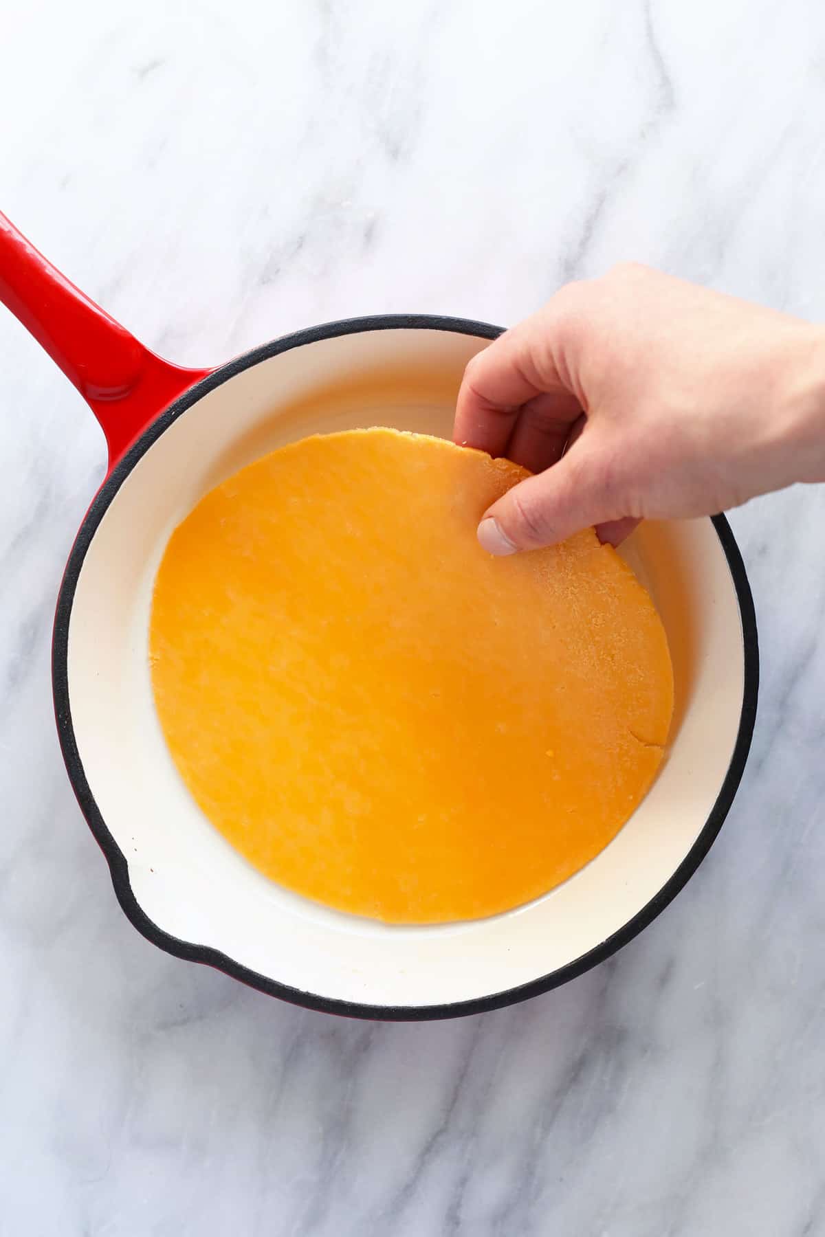 Placing a pice of cheese in a small skillet. 