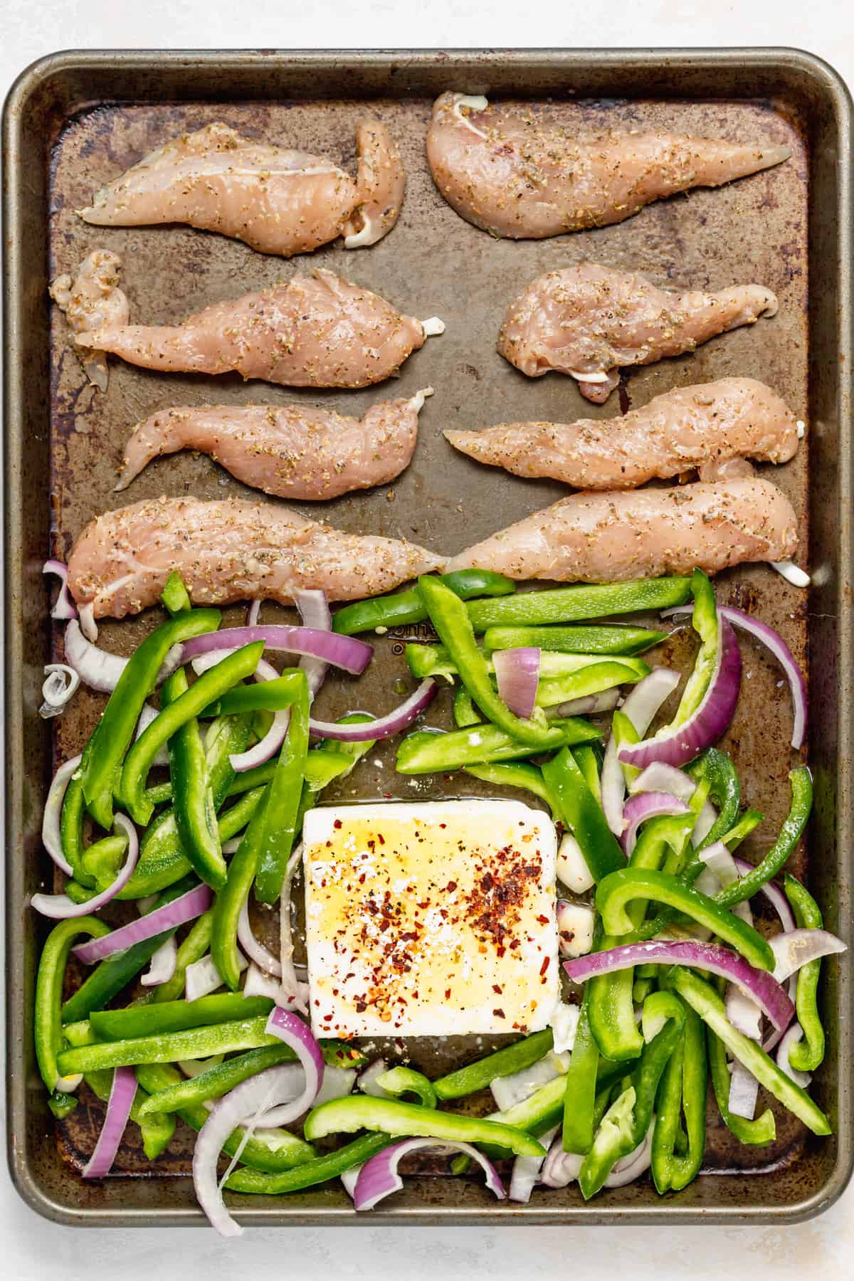 Chicken, vegetables, and feta on a baking sheet. 