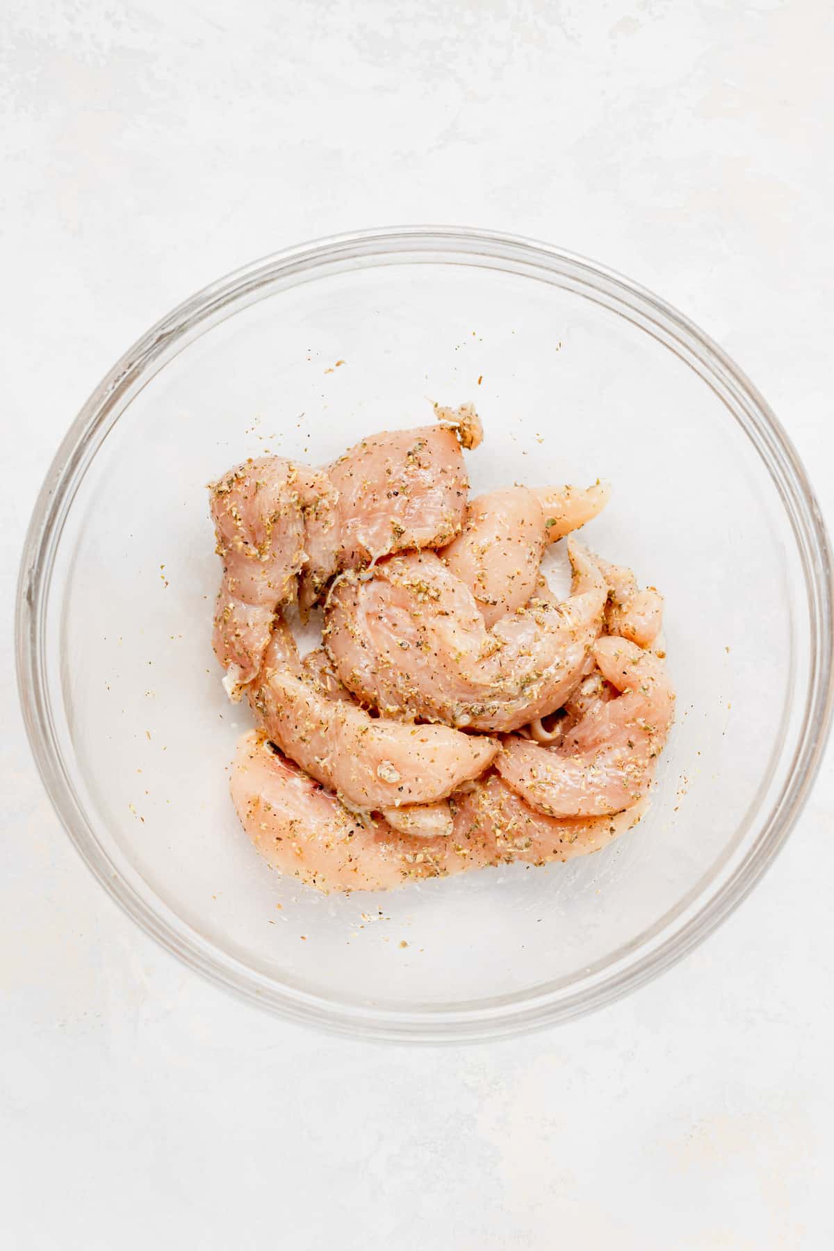 chicken tenders in a bowl with spices. 