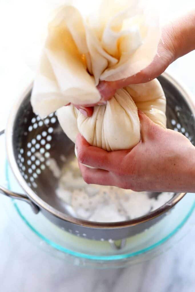 Straining excess whey from curd in cheese cloth. 