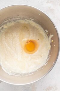 An egg in a metal mixing bowl for lemon ricotta cake.