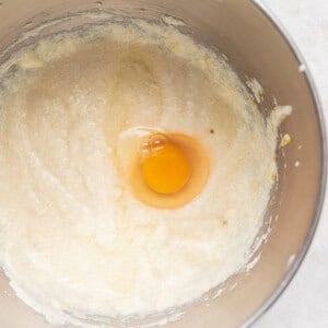 An egg in a metal mixing bowl for lemon ricotta cake.