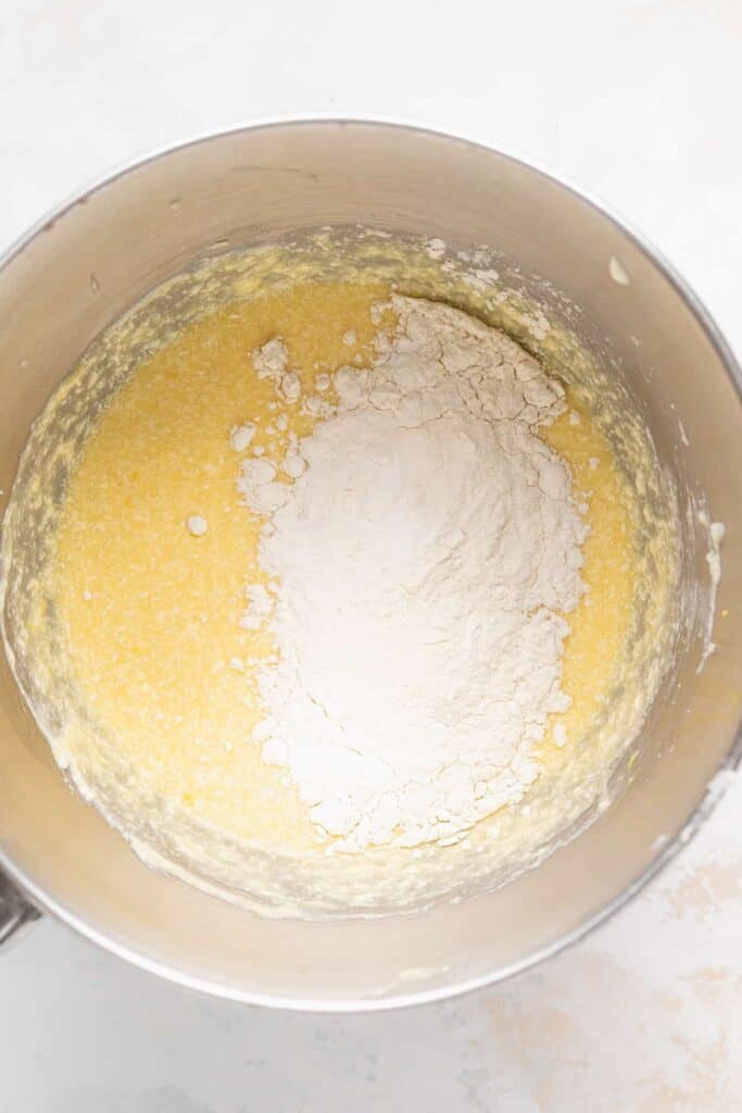 dry ingredients being added to lemon ricotta cake batter in a bowl