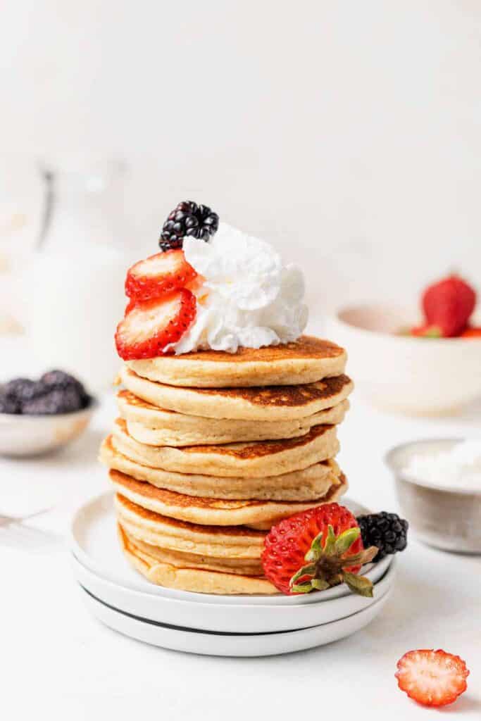 A stack of cottage cheese pancakes with whipped cream and berries on top. 