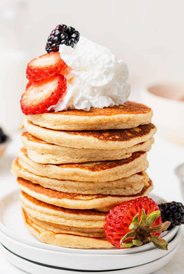 a stack of pancakes with whipped cream and berries.