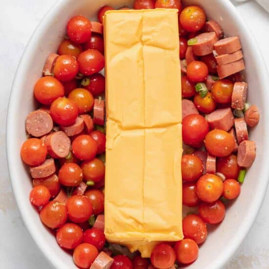 a white bowl with cheese, tomatoes, and sausage in it.