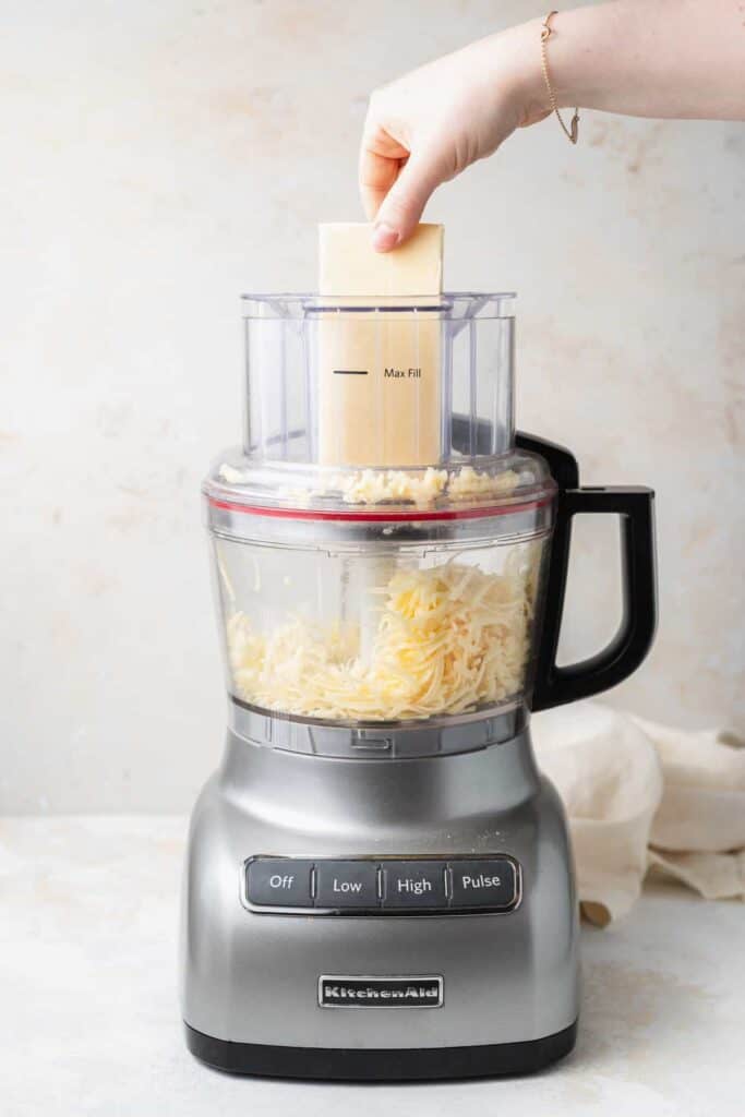grating white cheddar cheese in food processor.