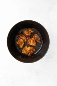 fried chicken in a black pan on a white surface.