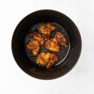 fried chicken in a black pan on a white surface.