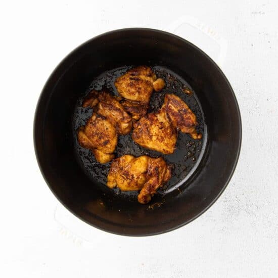 fried chicken in a black pan on a white surface.