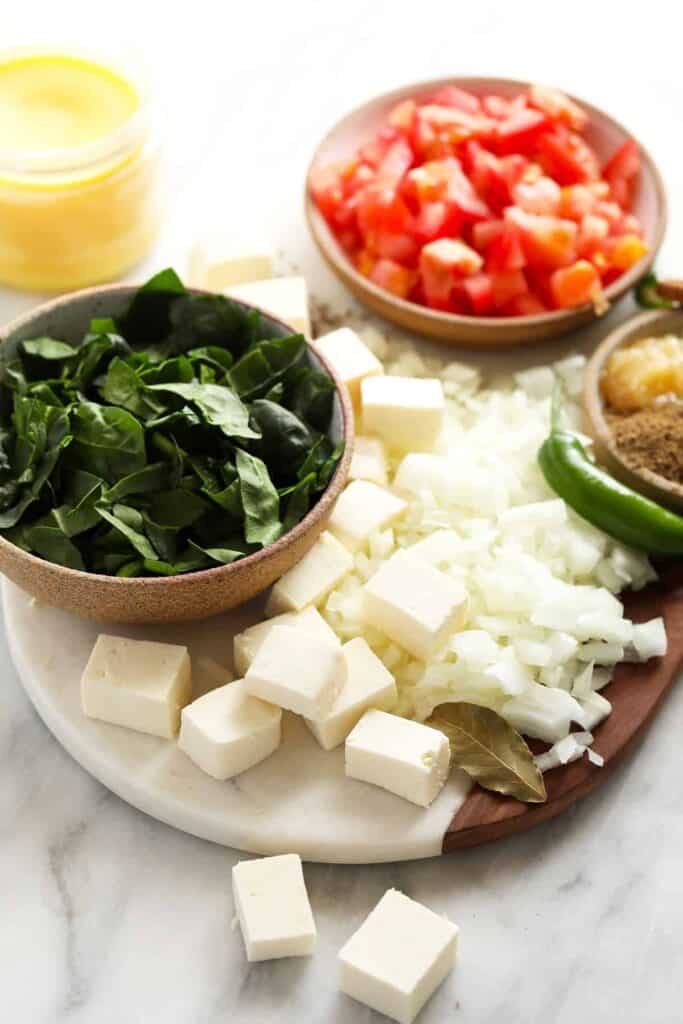 All the ingredients for palak paneer on a cutting board. 