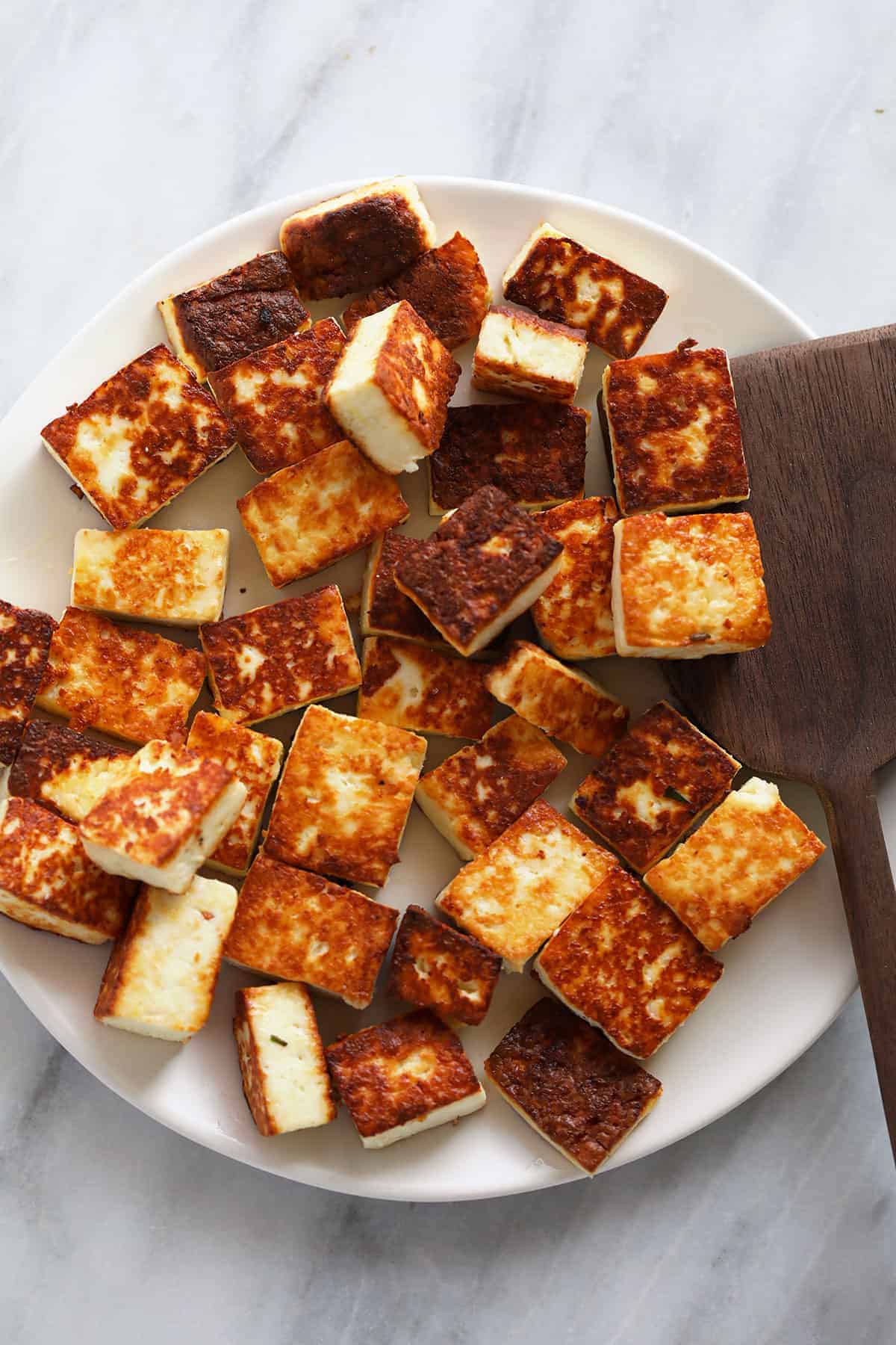 Browned paneer on a plate. 