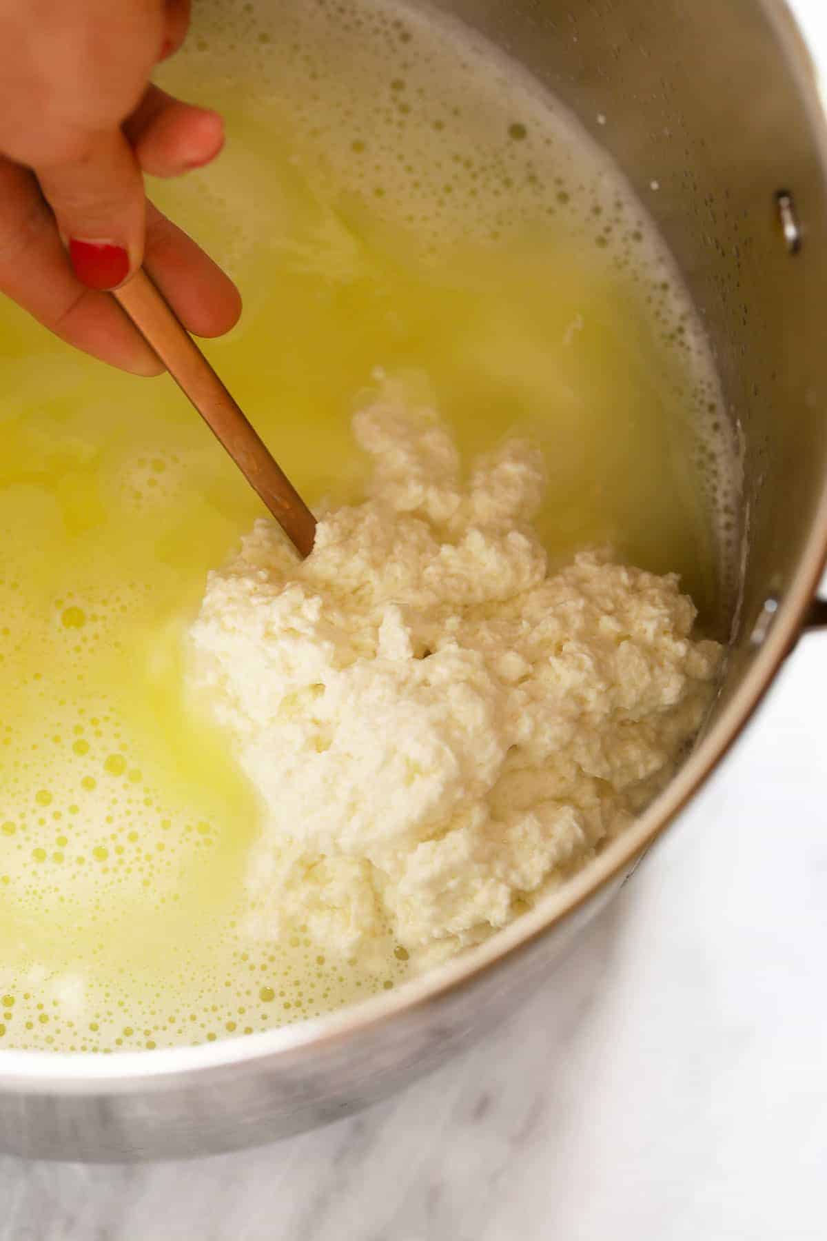 Paneer curd and whey in a pot. 