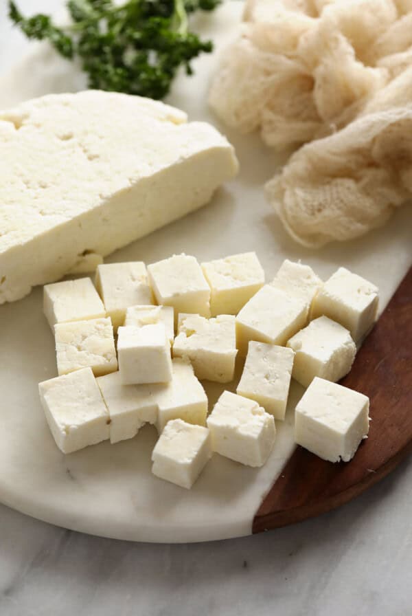 Cubed paneer on a cutting board.