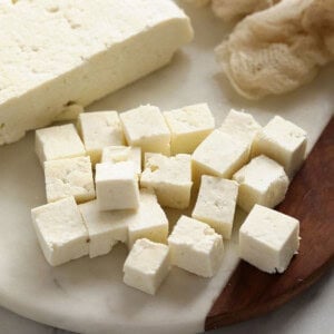 Paneer cut into cubes on cutting board