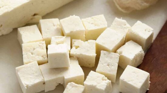 Paneer cut into cubes on cutting board