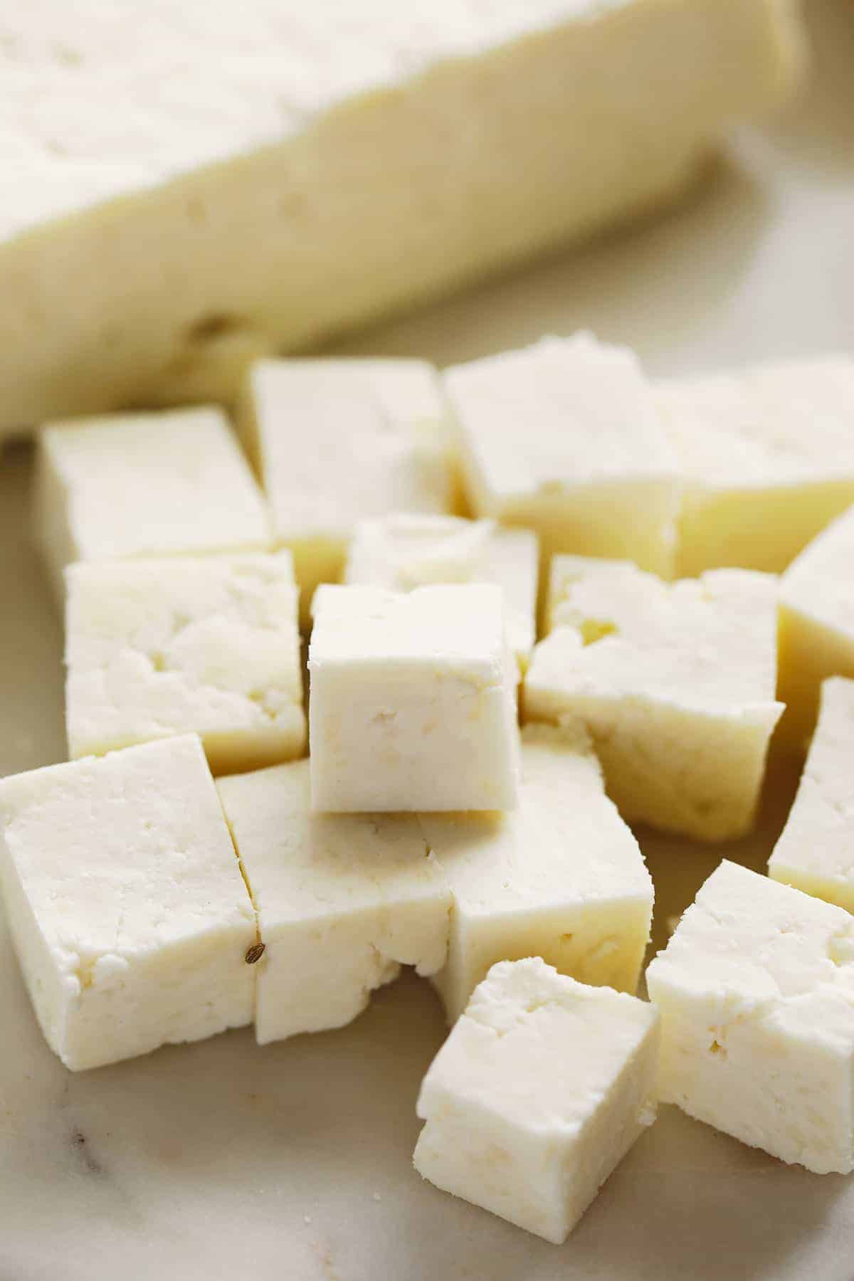 Fresh paneer cubes on a cutting board. 