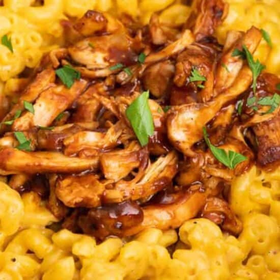 A bowl of macaroni and cheese with bbq chicken on top.