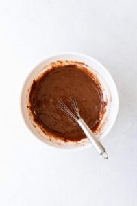 chocolate batter in a white bowl with a whisk.