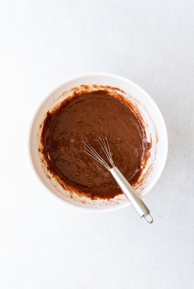 chocolate batter in a white bowl with a whisk.