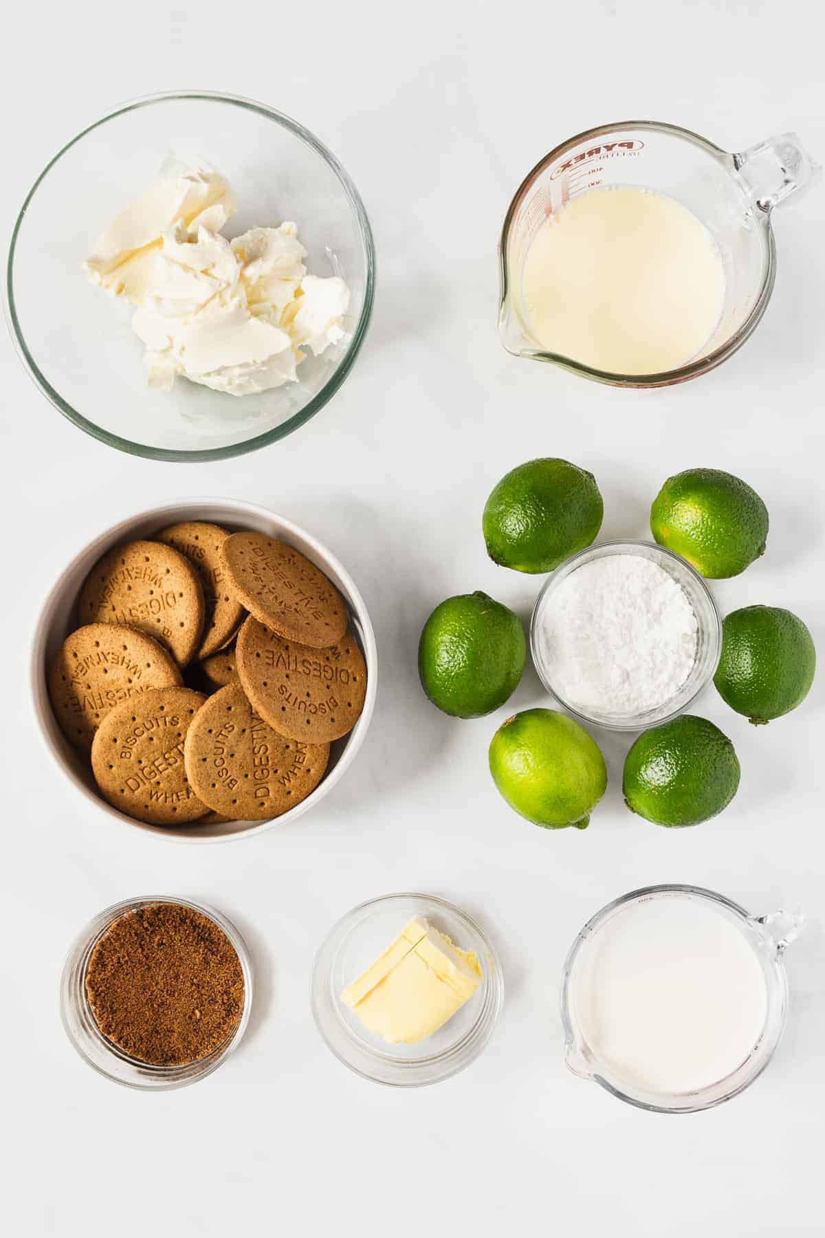 A photo of cream cheese, sweet and condensed milk, crackers, sugar, and limes. 