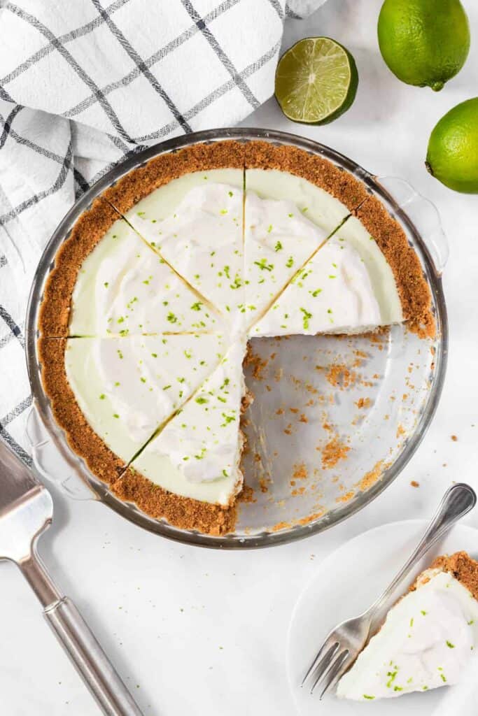 Two pieces missing from a key lime pie with cream cheese. 