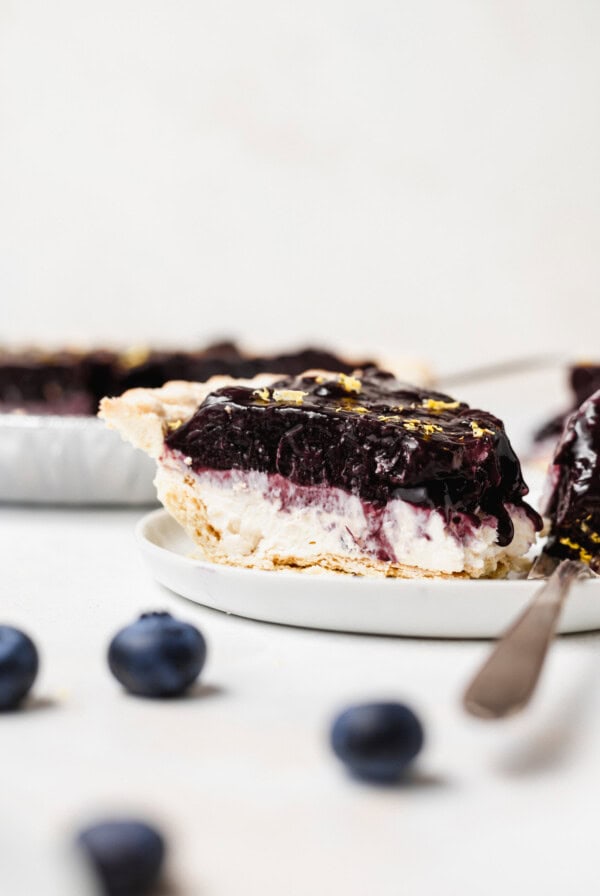 A slice of blueberry cream cheese pie on a plate.