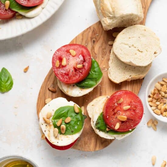 Caprese salad on a cutting board with slices of bread.