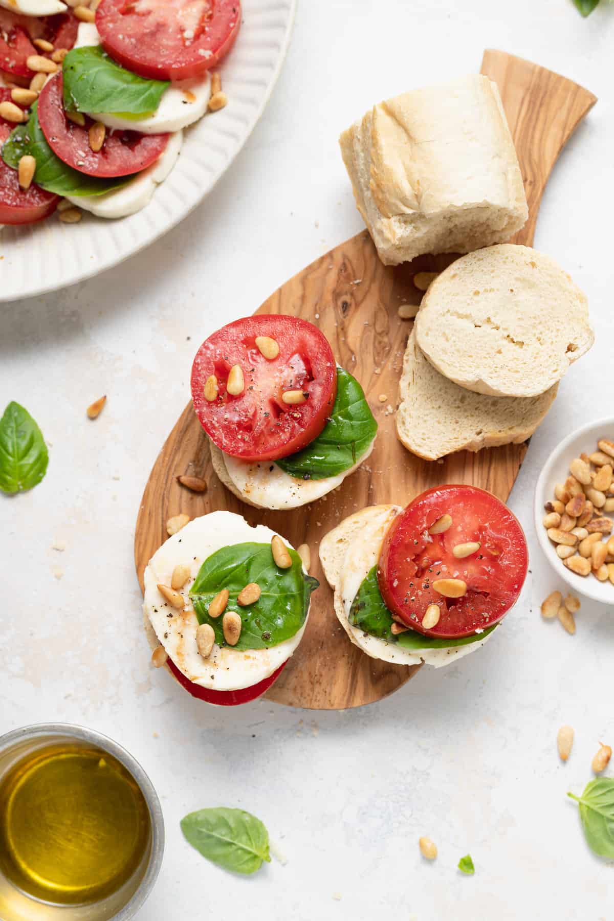 Caprese salad on a cutting board with slices of bread.