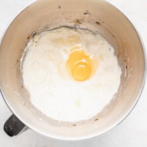 An egg cracked in a mixing bowl, ready for chocolate chip ricotta muffins.